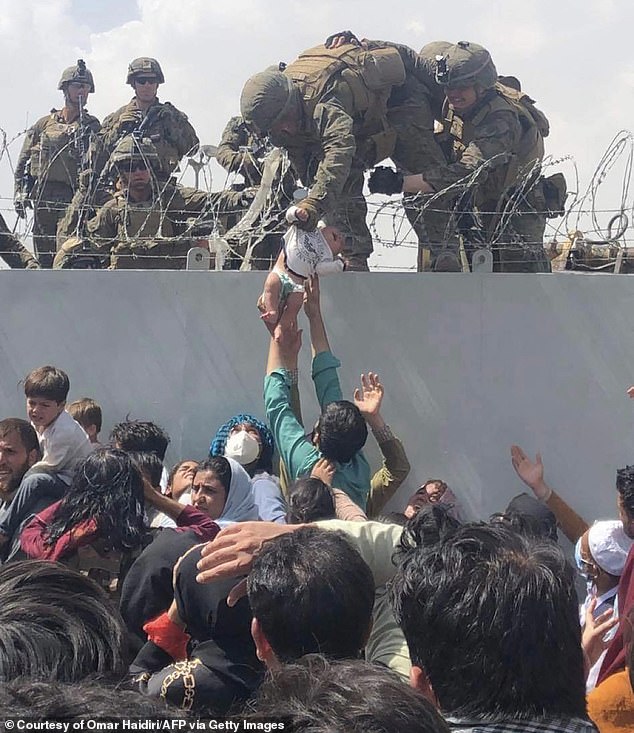 A U.S. Marine grabbed a baby over a barbed wire fence during an evacuation at Kabul's Hamid Karzai International Airport on August 19, 2021