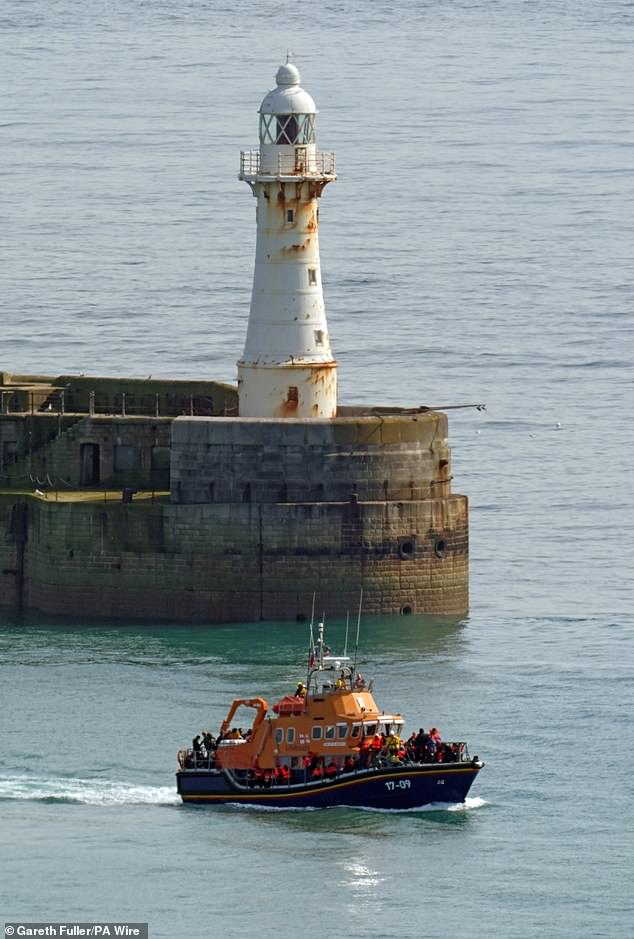 An RNLI rescue boat carrying a group of people, believed to be migrants, is taken to Dover, Kent, yesterday morning.