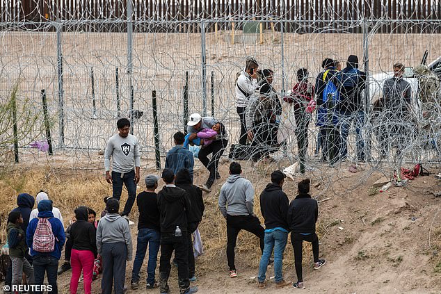 Migrants gather at concertina wire while camping on the US side, pleading with the Texas National Guard to allow them access to the border wall so they can seek asylum