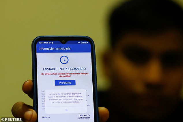 A migrant from Venezuela seeking asylum in the US uses his phone to make an appointment