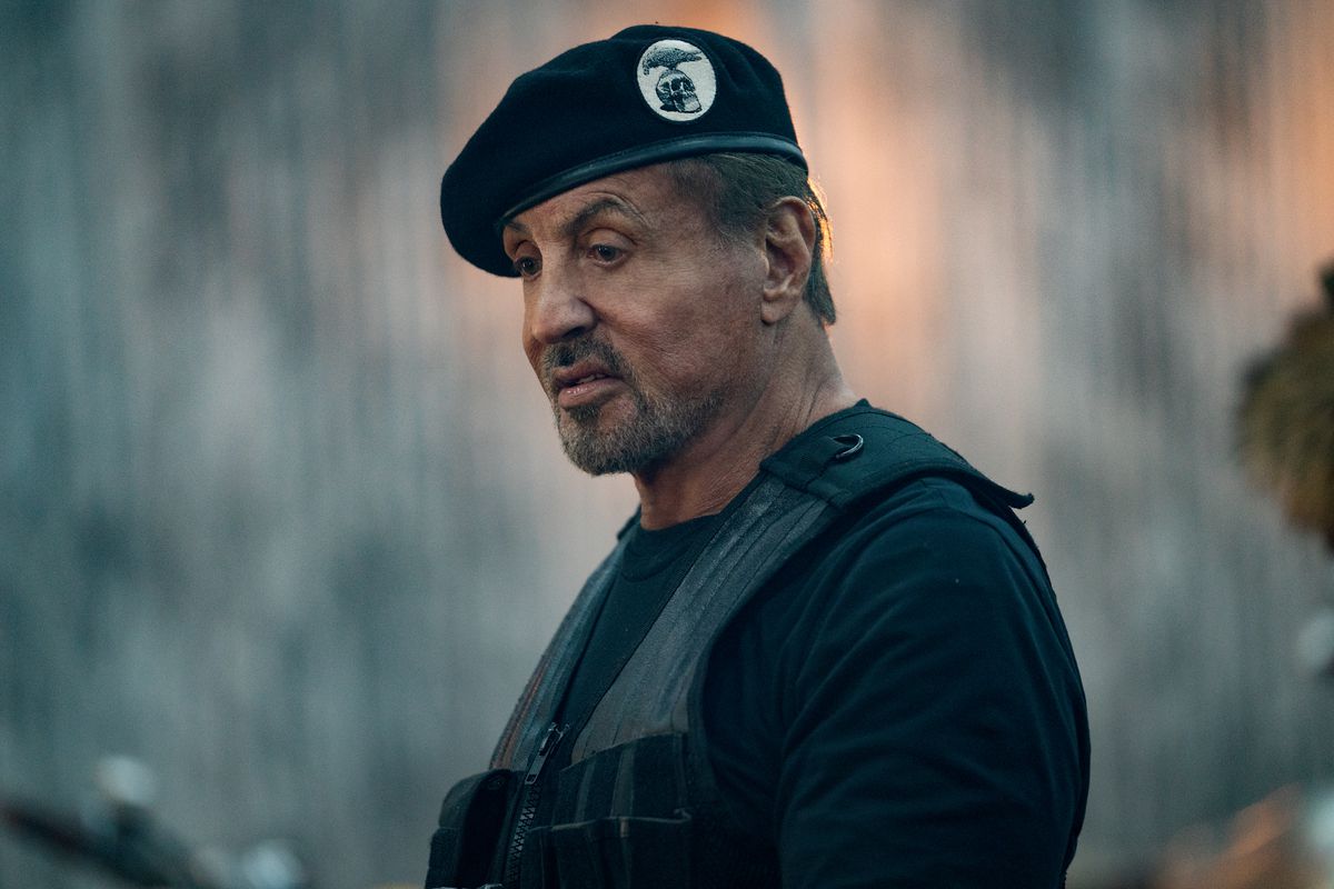 A mid shot of Sylvester Stallone wearing a black beret and vest in the movie Expend4bles.