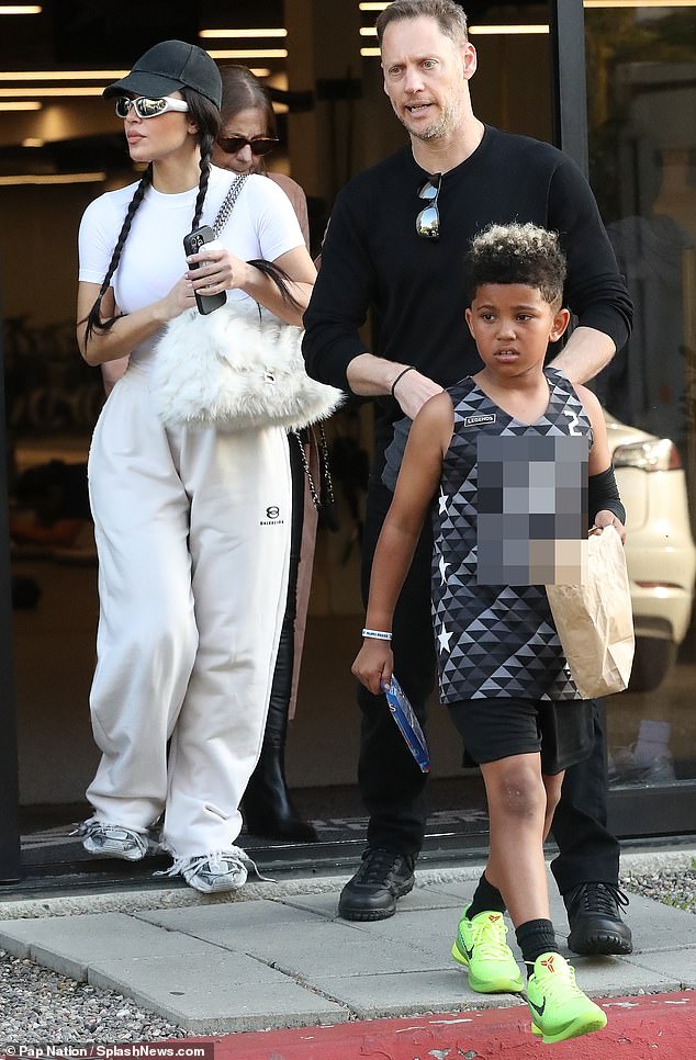 Little Saint looked adorable in a black, gray and white basketball jersey and lime green Nike sneakers