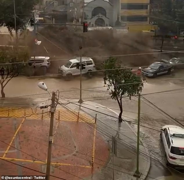 Floodwaters poured over the reservoir wall in La Paz as heavy rain devastated the Bolivian capital on Wednesday, sending vehicles sliding onto the streets