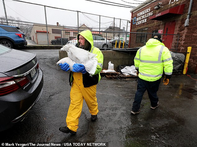 Yonkers Department of Public Works employees carry sandbags to waiting Yonkers residents as they distribute them at the Yonkers Recycling Center