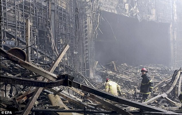 Rescuers clear rubble and extinguish fires in the lobby of Crocus City Hall