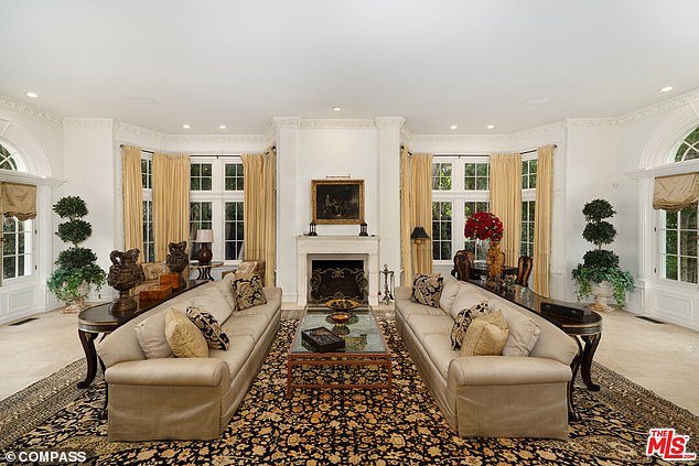 A spacious living room complete with fireplace and patio doors lead to the garden