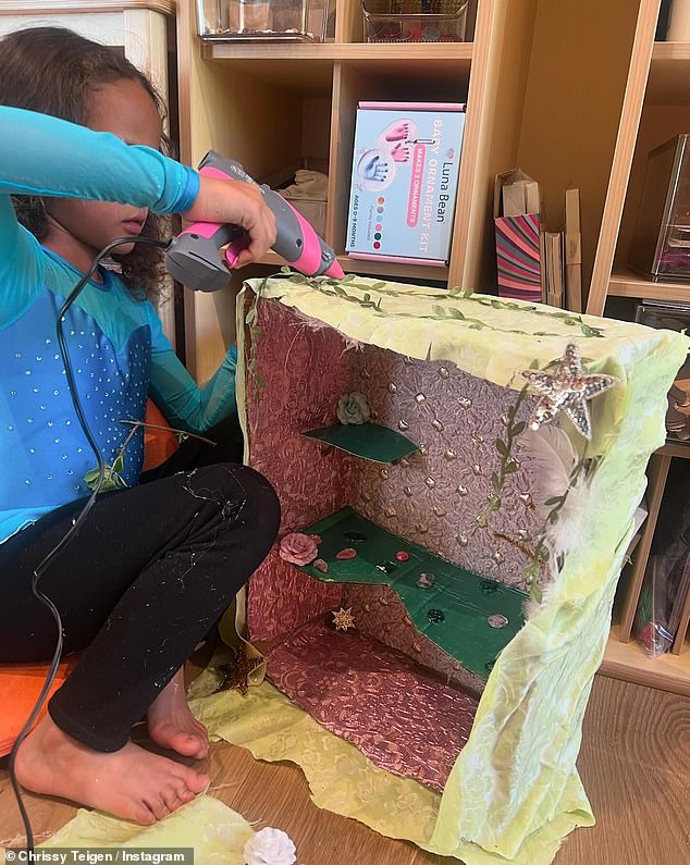 The model supervised her child as she applied a dab of hot glue to a diorama