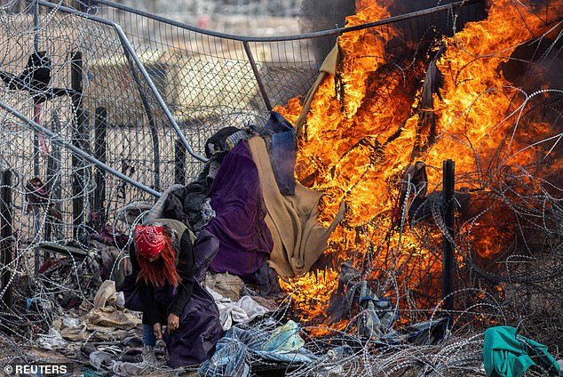 A migrant checks her bag after members of the Texas National Guard burned clothing used by migrants to break through barbed wire and a fence to enter the U.S. and surrender