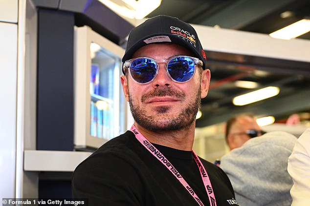 Efron kept it casual in a black long-sleeved T-shirt and opted for stylish sunglasses as he watched in the Oracle Red Bull Racing garage