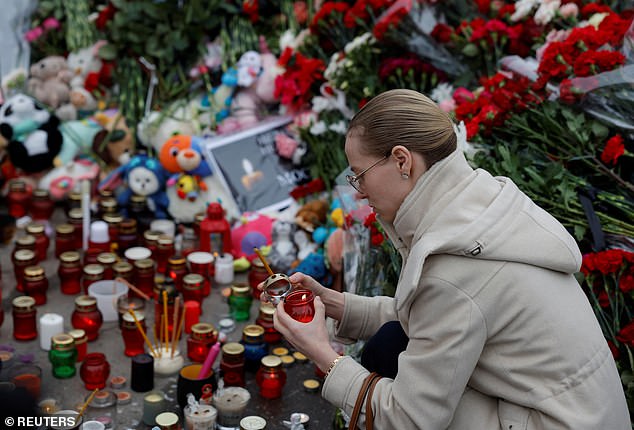 A woman lights a candle at a makeshift memorial to the victims of a shooting outside the Crocus City Hall concert venue in the Moscow region, Russia, March 24