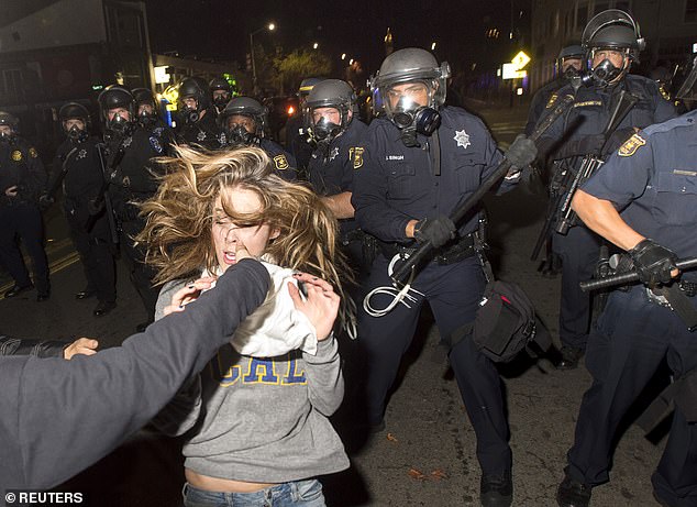 A protester near Berkeley flees as police officers try to disperse a crowd made up largely of student demonstrators during a protest against police brutality in the US.