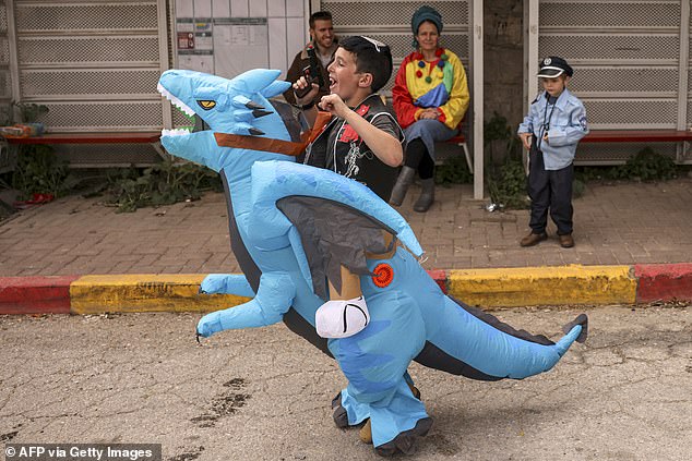 A boy dressed in a costume depicting a blue dragon walks along Al-Shuhada Street, largely closed to Palestinians, in the divided city of Hebron in the occupied West Bank during festivities today.