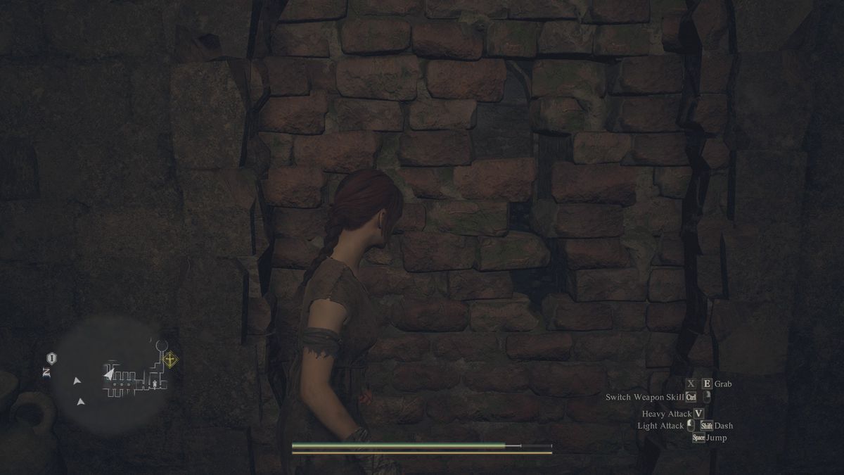 A hero from Dragon's Dogma 2 looks at a crumbling wall in a prison cell.