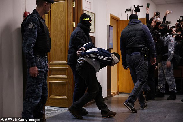 A man suspected of taking part in the attack on a concert hall that killed 137 people, the deadliest attack in Europe ever claimed by the jihadist group Islamic State, is being escorted by Russian law enforcement officers.