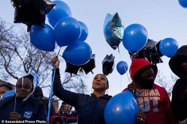 Alicia Perkins, center, an aunt of Jayden Perkins' father, holds balloons outside Perkins' home in Chicago at a memorial for Jayden, who was murdered