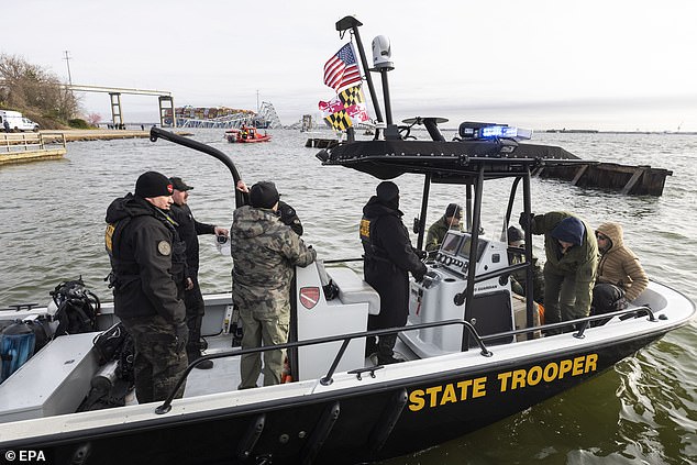 Rescue personnel gather on the banks of the Patapsco River during search and rescue efforts