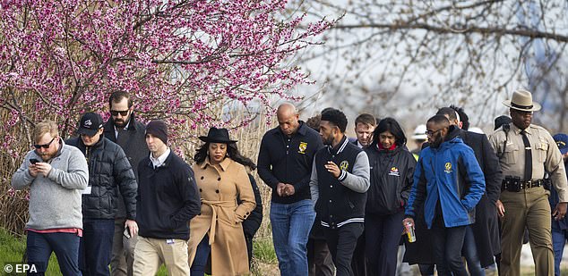 Maryland Governor Wes Moore (C) walks with staff and law enforcement officers along the shore of the Patapsco River