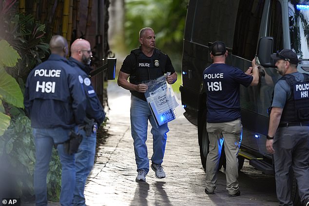 A law enforcement officer carries an evidence bag to a van at Diddy's Miami home after the raid