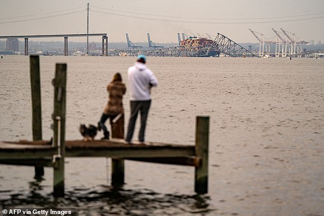 People look out at the Francis Scott Key Bridge following its collapse after the Singapore-flagged container ship Dali collided with it along the Patapsco River on March 26.
