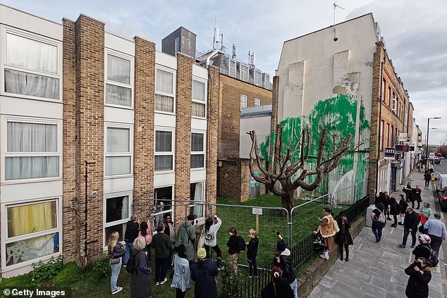 The public looks at a mural by artist Banksy on March 20 after it was damaged with white paint