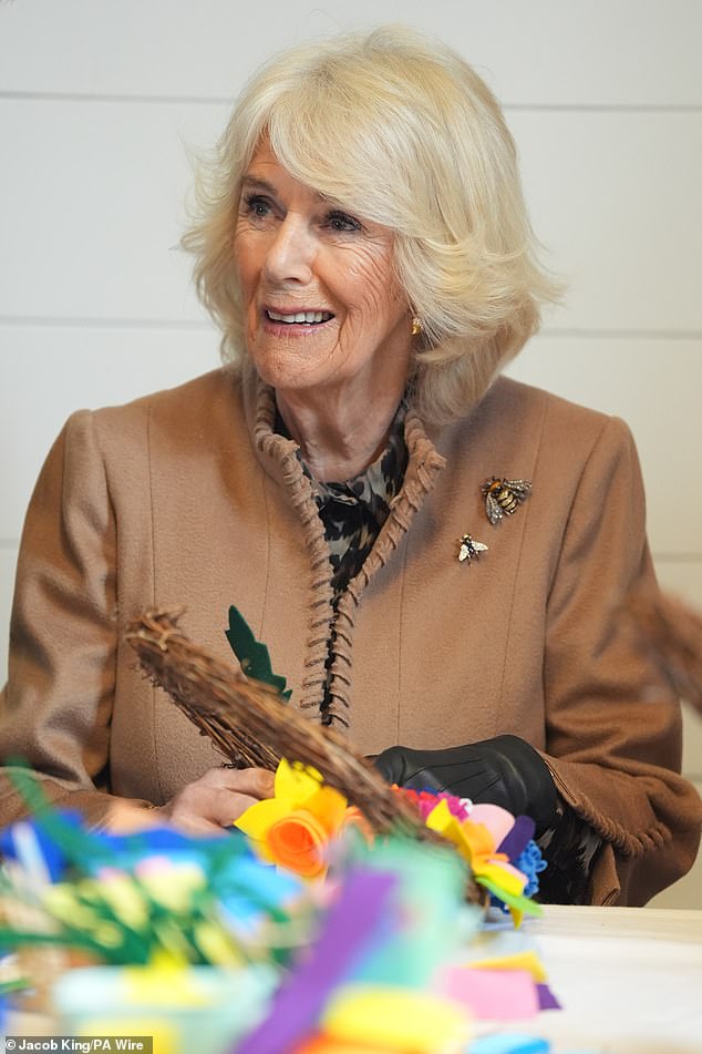 The Queen, pictured making a spring wreath during today's visit, spoke to a woman who lost her husband to cancer during her visit to an 18th century mill in Shrewsbury