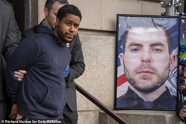 Officials say Jones was behind the wheel of a car illegally parked in a bus lane, causing Diller and his partner to approach them shortly before 6 p.m. Monday.  Pictured: Jones was seen walking past Diller's photo as he left the 101 precinct on Wednesday