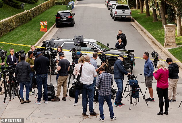 Media members work as law enforcement officers stand behind the police tape of Diddy's home in Holmby Hills