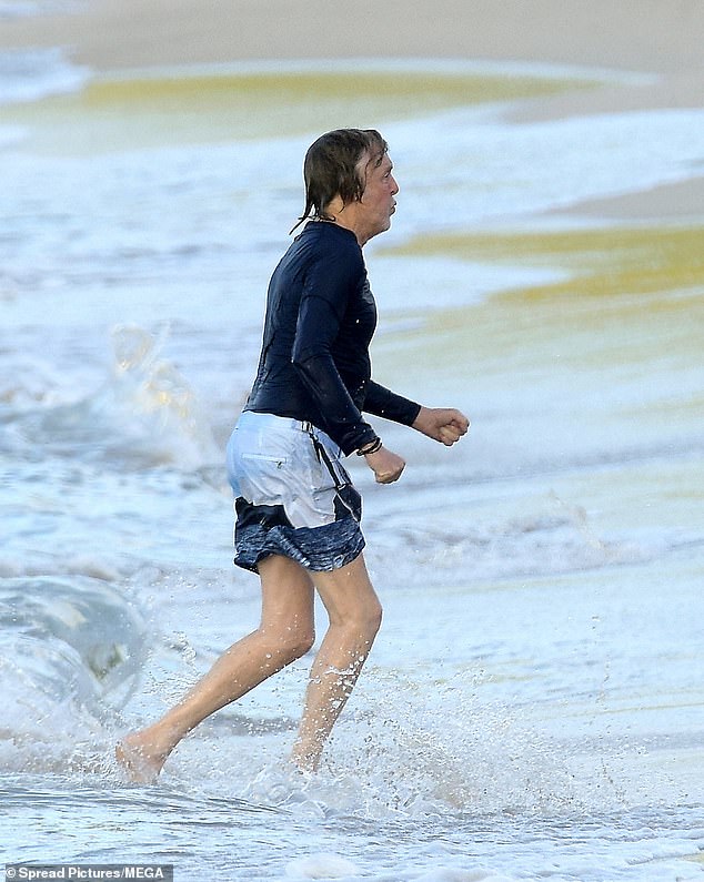Wearing colorful swim shorts and a long-sleeved navy top, Paul looked incredibly relaxed as he frolicked in the ocean