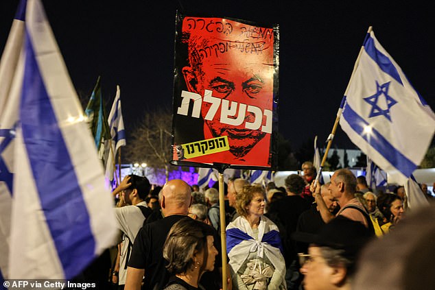 Protesters hold up signs demanding Netanyahu leave office.  Families of hostages say the prime minister is an 'obstacle to a deal'