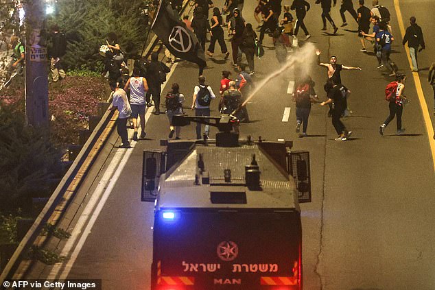 Police break up demonstrators blocking a road using water cannons