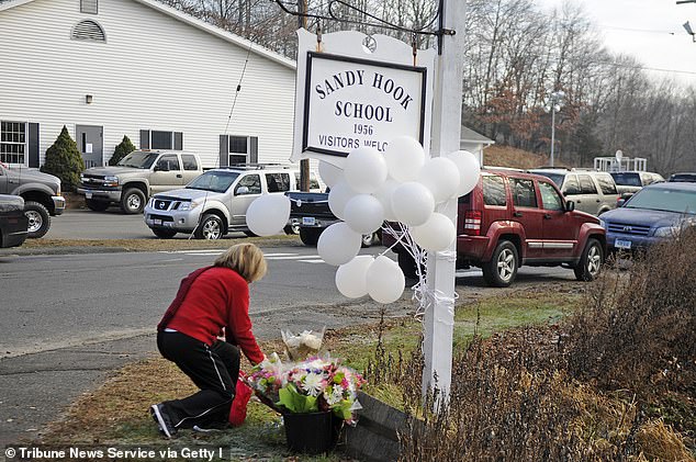 A woman places flowers at the sign in front of Sandy Hook Elementary School on December 15, 2012