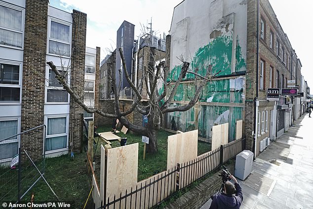 Plastic screens and wooden fencing have been placed over Banksy's latest mural on the side of a block of flats in Islington