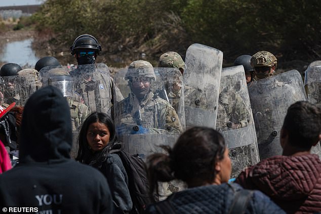Texas State Troopers stand guard blocking migrants camping along the riverbank, at the US-Mexico border, near El Paso, Texas