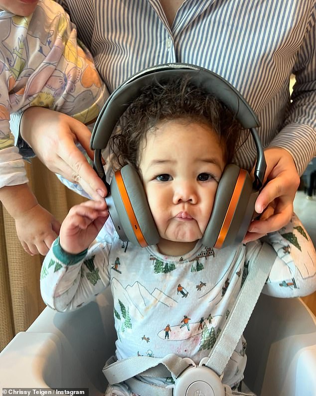 Then, Teigen's daughter Esti was caught having her cheeks squished by large headphones while she was strapped into her high chair.