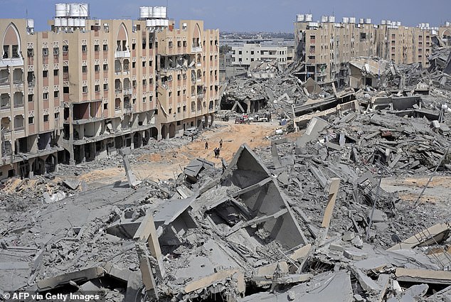 Displaced Palestinians walk through a rubble-filled street in the Hamad area, west of Khan Yunis in the southern Gaza Strip