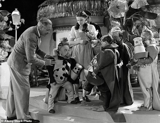 Pictured: Director Victor Fleming adjusts a munchkin's blocking on set