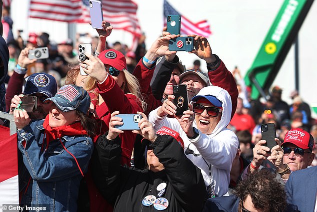 Guests take photos as the plane of Republican presidential candidate, former President Donald Trump, lands