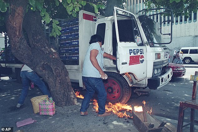 A Pepsi-Cola truck driver in Manila is seen trying to put out the fire under his truck after it was bombed by protesters in September 1993.  Such demonstrations were common that year, after an accident with a then new promotional campaign.