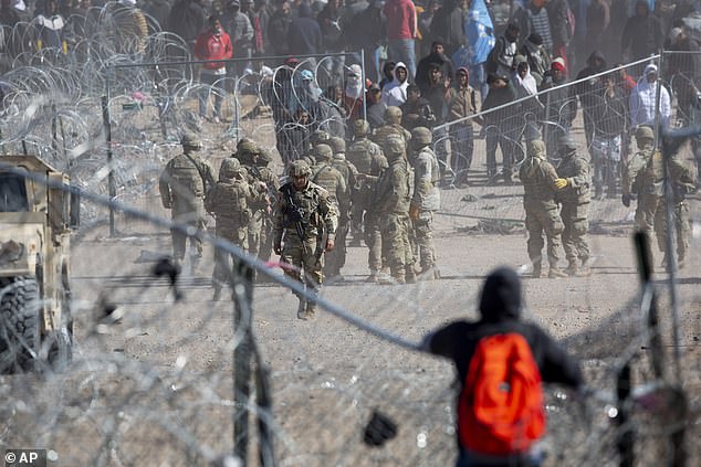 A migrant watches the aftermath of when about 100 men pushed through razor wire erected by the Texas National Guard outside El Paso on Thursday