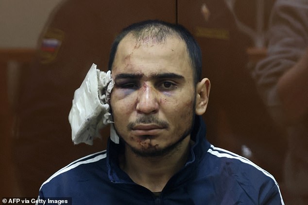 Saidakrami Murodali Rachabalizoda, suspected of taking part in the attack on a concert hall, sits in the suspect's cage with a severed ear believed to have been fed to him.