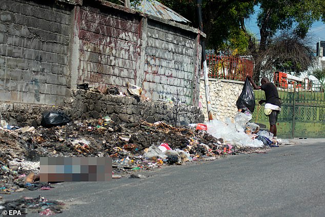 A man throws trash next to the body of a murdered person in Port-au-Prince on Friday