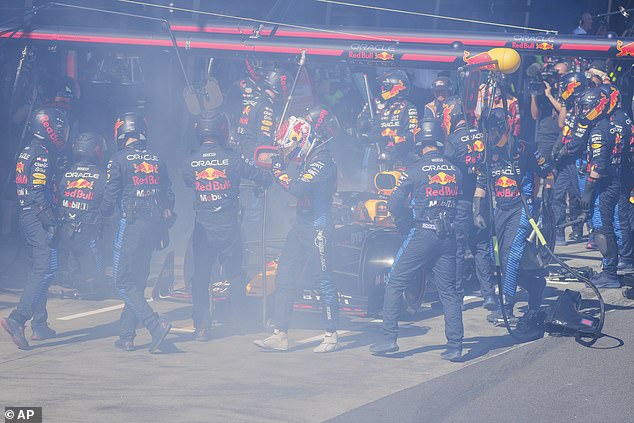 Verstappen (centre) is pictured getting out of his Red Bull after the pit crew battled flames coming from the right rear brake