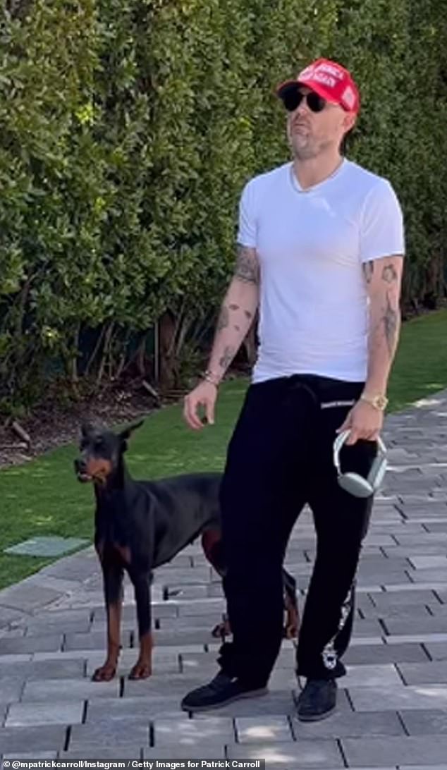 Patrick Carroll pictured in the driveway of his ultra-luxury home with one of his dogs as four police vehicles pull up outside his home