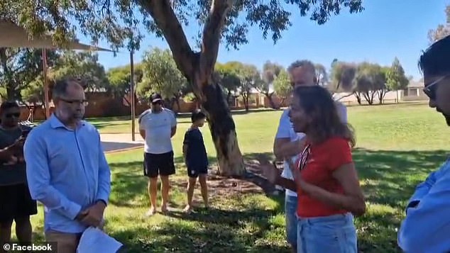 Dr.  Aly (right) was led away from the activists (left) by her husband Dave Allen and a staff member as the activists called her a 'coward'