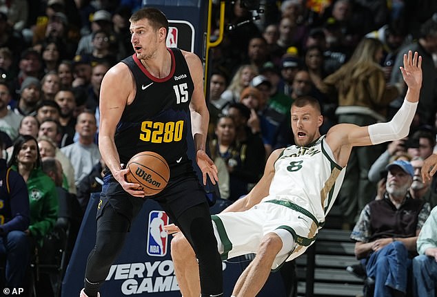 Denver Nuggets center Nikola Jokic, left, knocks over Boston Celtics center Kristaps Porzingis