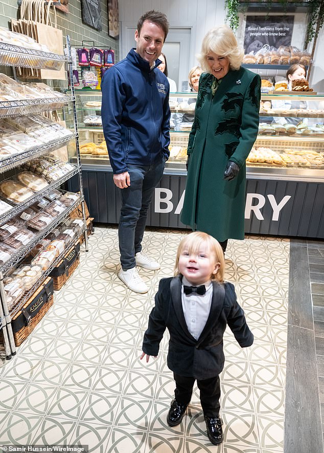 Queen Camilla was photobombed by an adorable one-year-old on Thursday as she visited local shops during a visit to Belfast