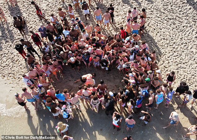 Excited spring breakers gather around some boys wrestling on the sand in Fort Lauderdale, Florida