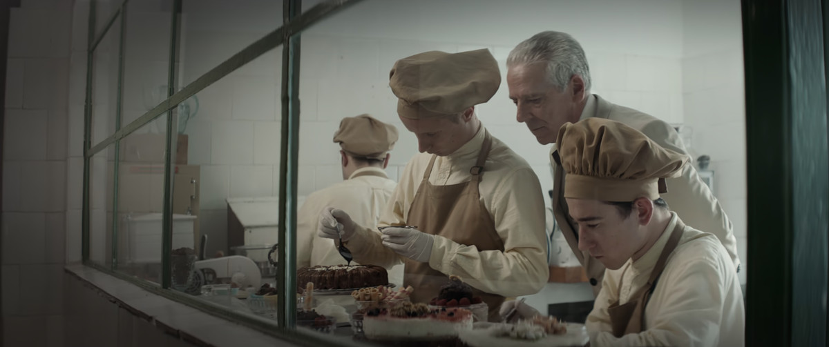 A chef looking over the shoulder of two people preparing pastries in The Platform