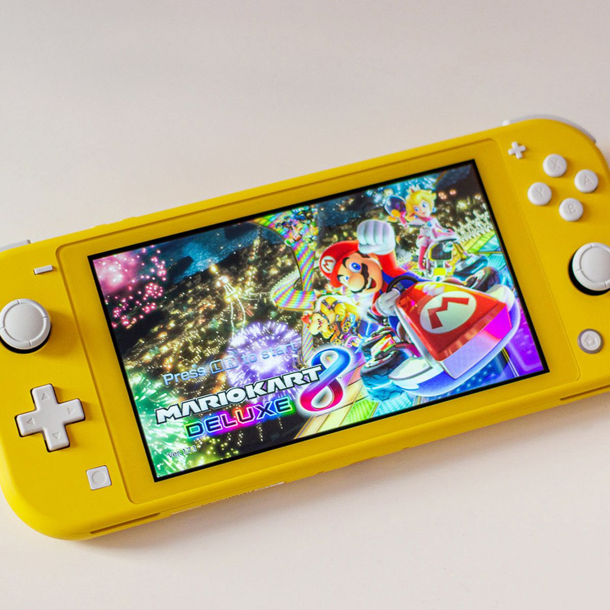 a yellow Nintendo Switch Lite with the Mario Kart 8 Deluxe home screen on it