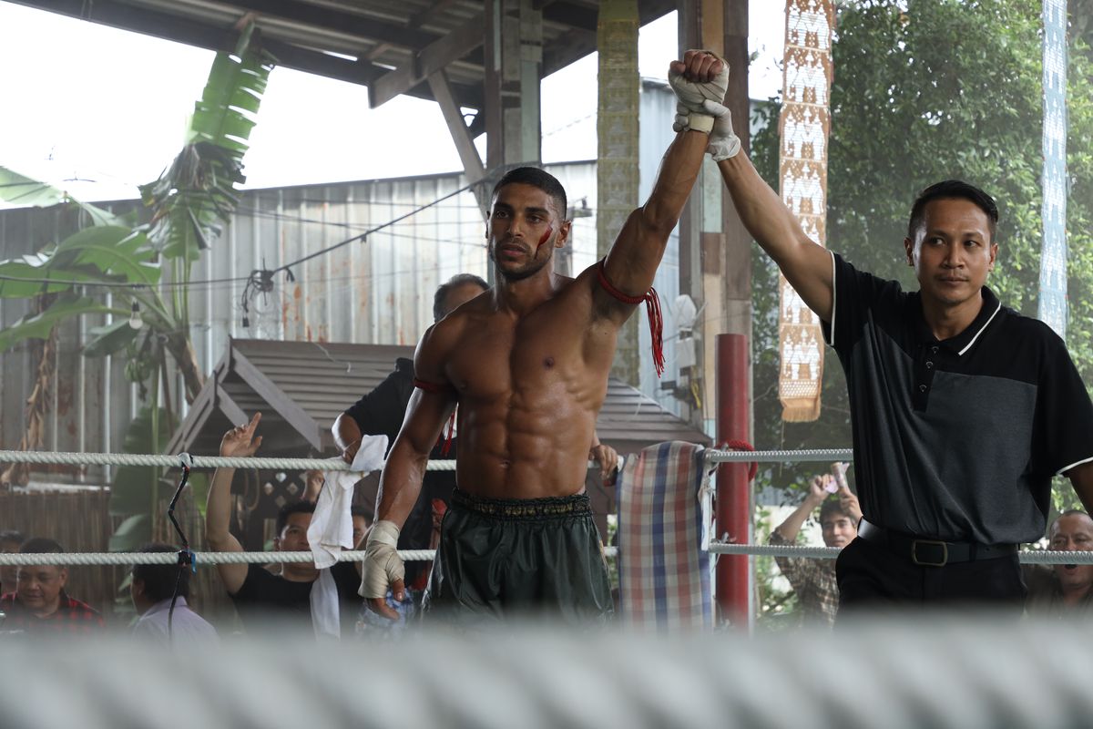 Nassim Lyes, looking absolutely torn, gets his arm raised in the ring after a fight in Mayhem!